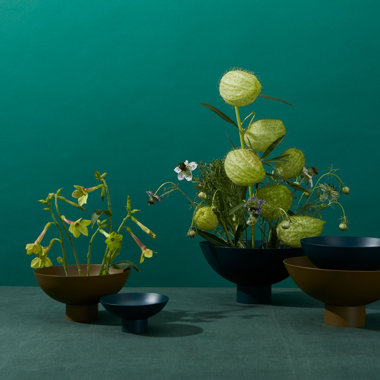 Group of Essential Footed Bowls in various colors and sizes arranged with flowers.