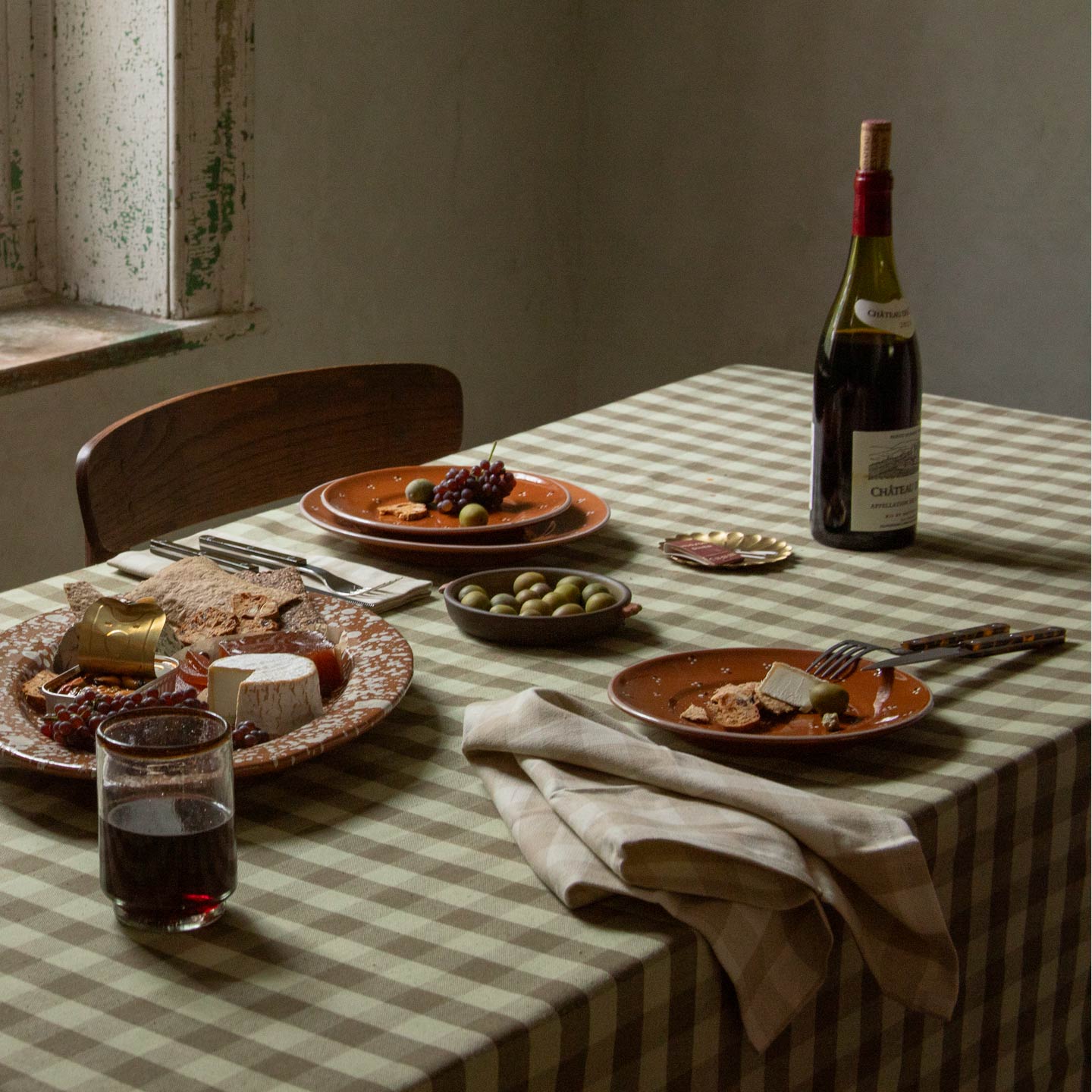 Tabletop with cheese plate and wine and Essential Gingham Napkin in Ivory.