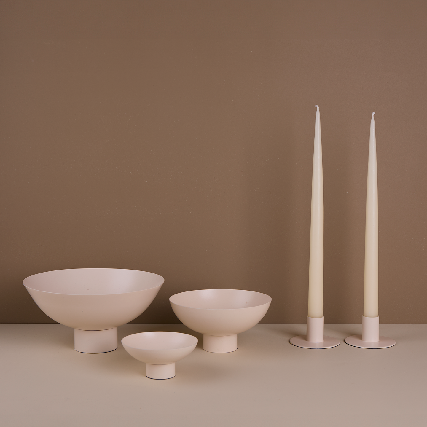 A trio of footed bowls and pair of candle holders, all in Ivory, with ivory taper candles.