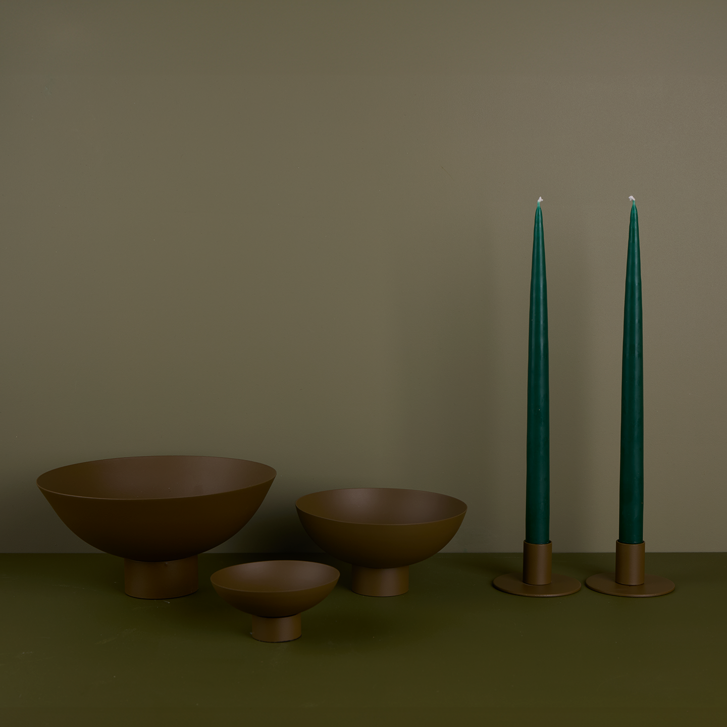 A trio of footed bowls and pair of candle holders, all in Olive, with green taper candles.