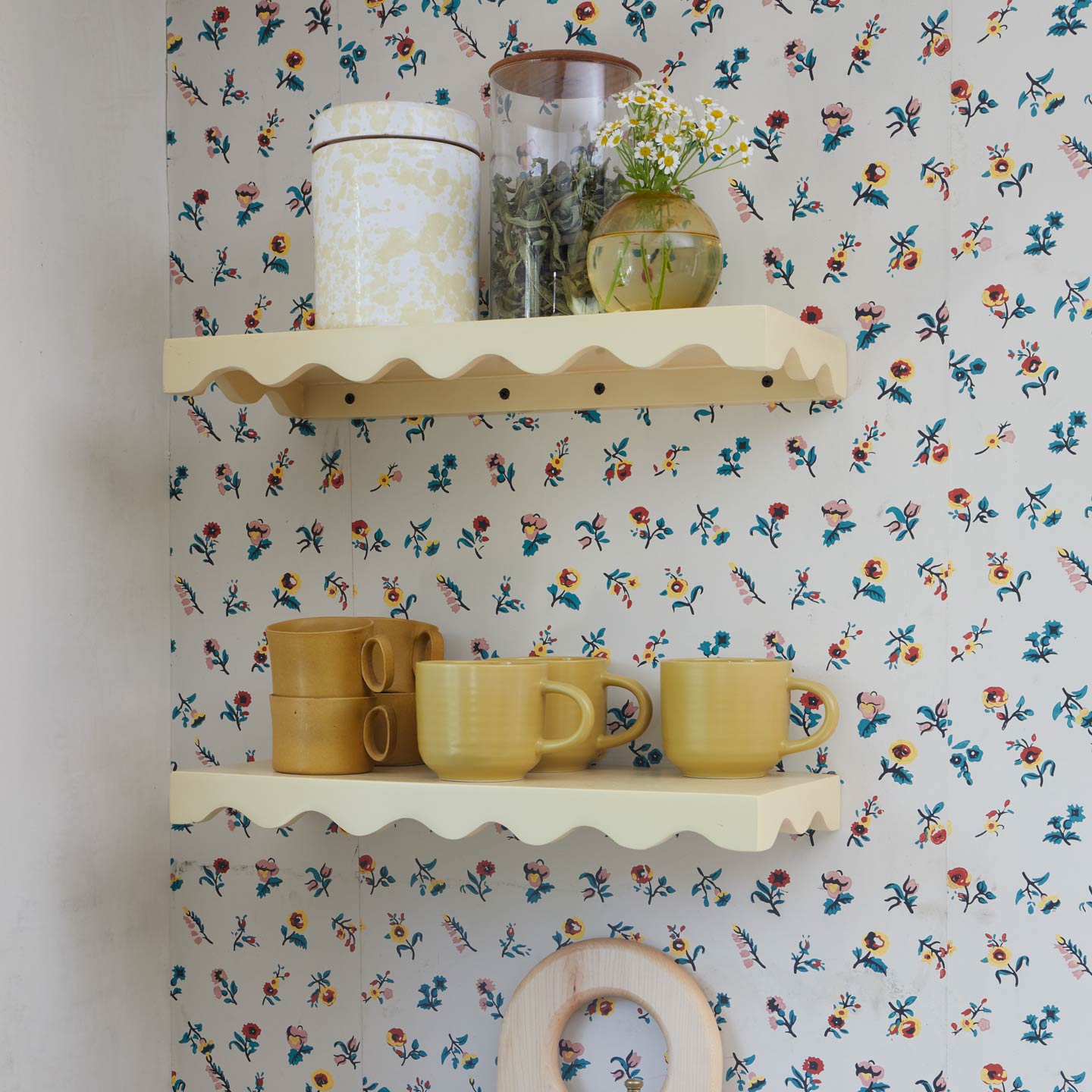 Shelves with floral wallpaper background with various kitchen and storage items.