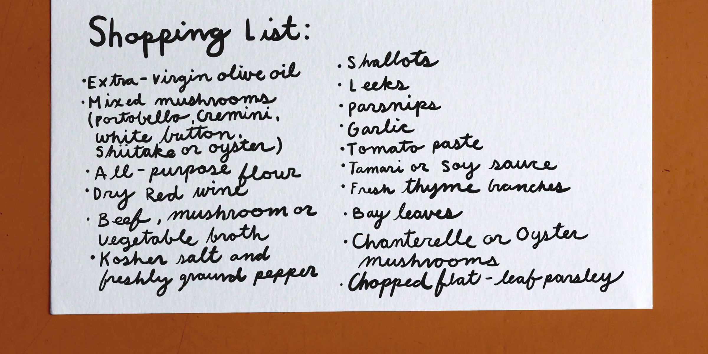 A handwritten shopping list on white paper includes items such as extra-virgin olive oil, mixed mushrooms, all-purpose flour, dry red wine, garlic, tomato paste, and fresh thyme branches.