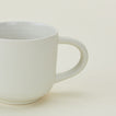 A white ceramic mug with a handle, positioned against a light background.