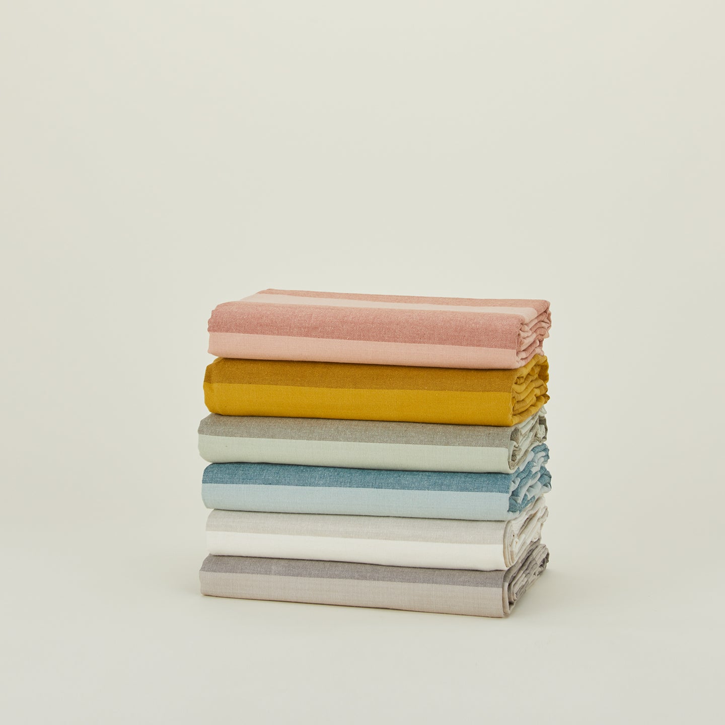 Stack of folded Essential Striped Tabecloths in various colors.