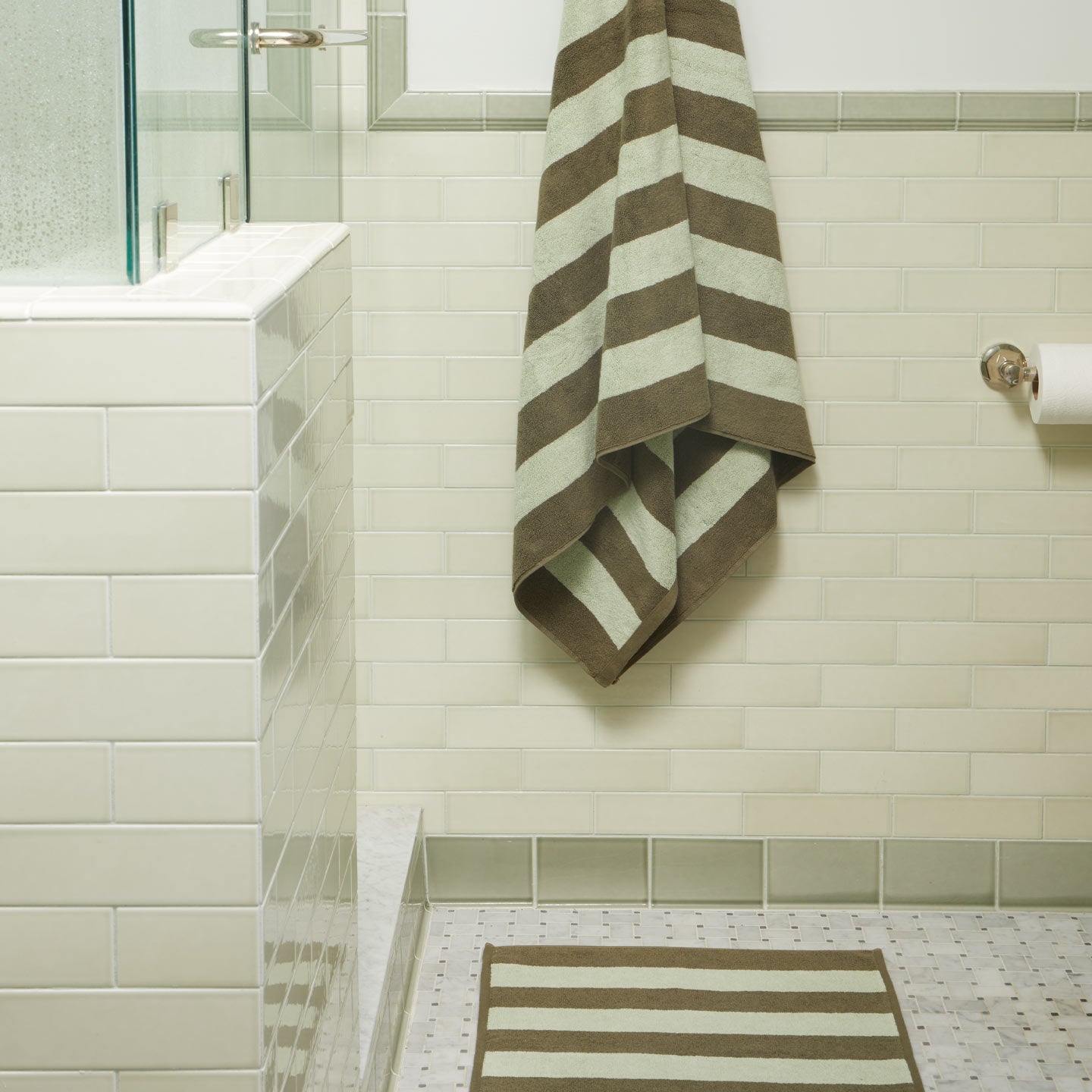 Bathroom with striped towel and rug on tiled floor