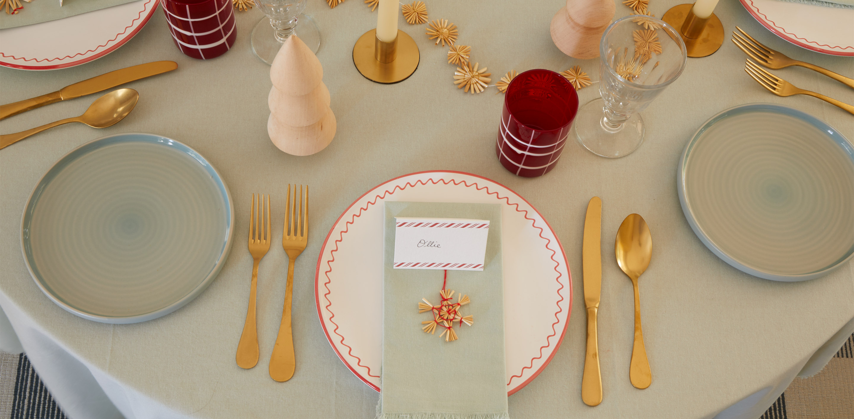 A festive place setting with straw garland and a placecard with small straw ornament attached