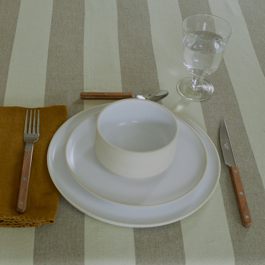 Placesetting on Essential Striped Tablecloth in Olive and Sage and teak flatware.