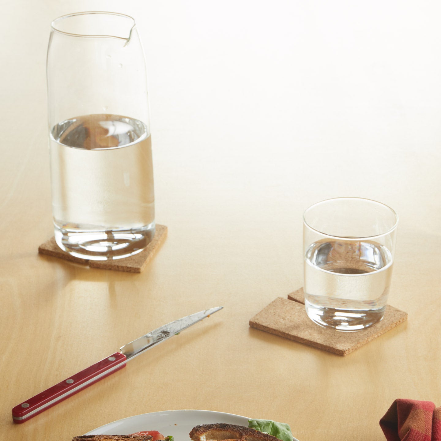 Essential Glass Pitcher with Essential Glass with water on tabletop.