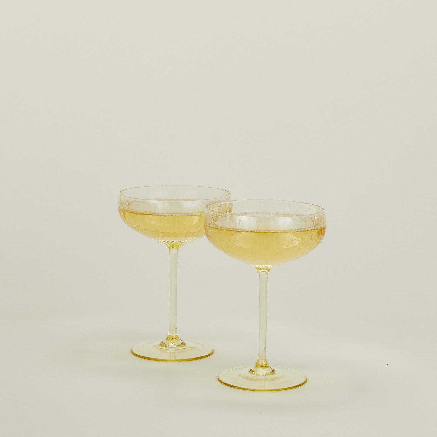 Set of two ribbed amber cocktail coupe glasses with champagne.