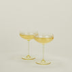 Set of two ribbed amber cocktail coupe glasses with champagne.