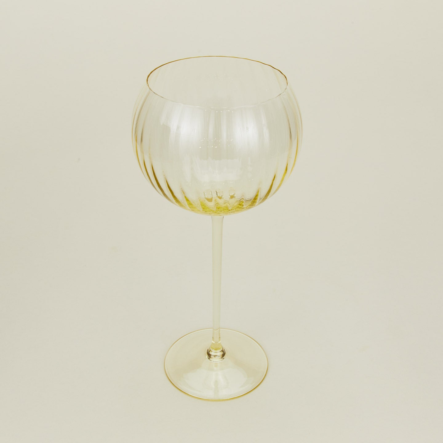 Three-quarter angle of ribbed amber wine glass.