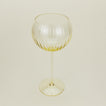 Three-quarter angle of ribbed amber wine glass.