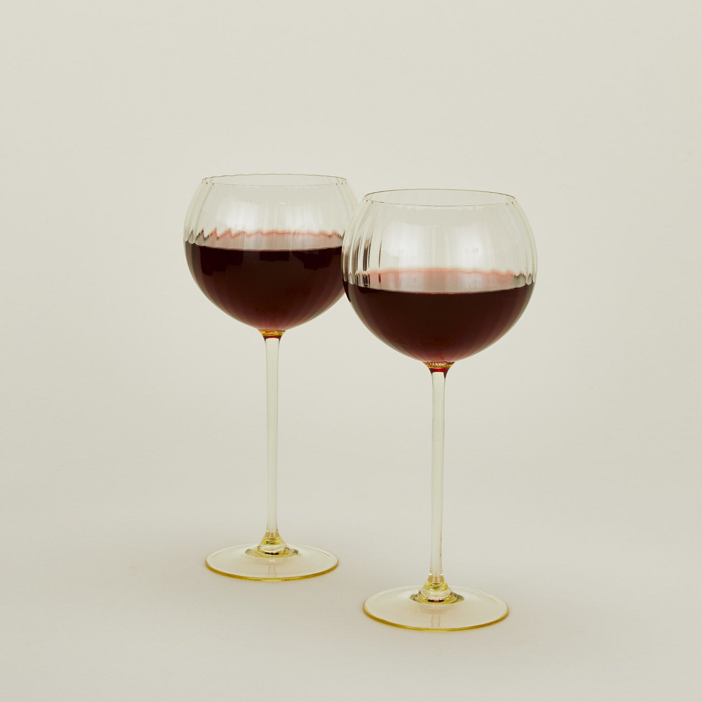 Set of two ribbed  amber wine glasses with red wine.