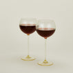 Set of two ribbed  amber wine glasses with red wine.