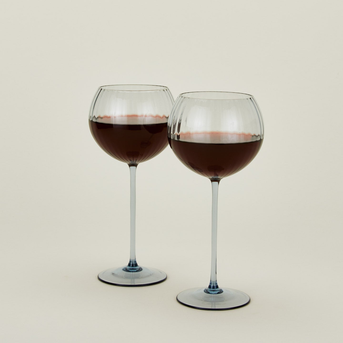 Set of two ribbed  blue wine glasses with red wine.