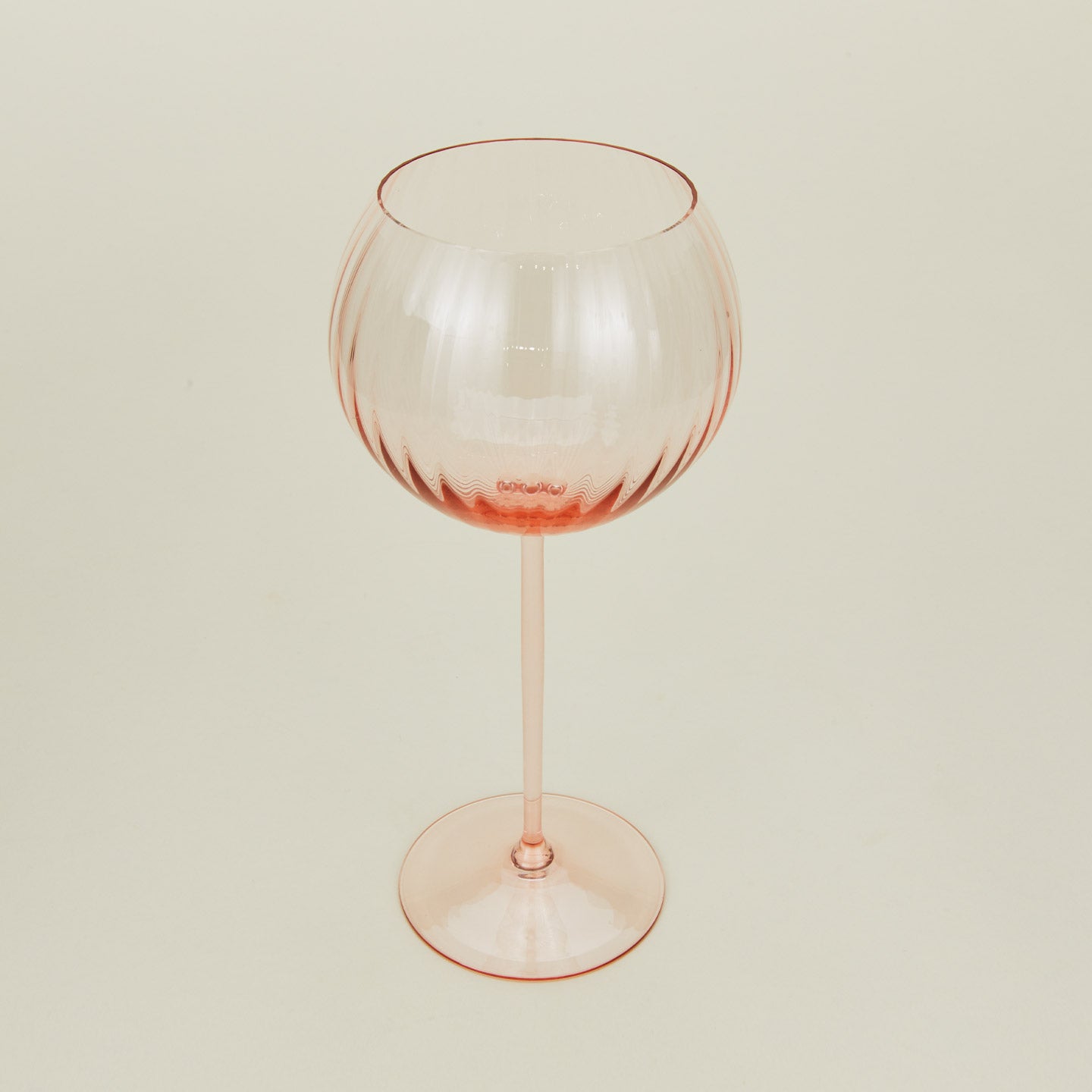 Three-quarter angle of ribbed blush wine glass.