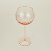 Three-quarter angle of ribbed blush wine glass.