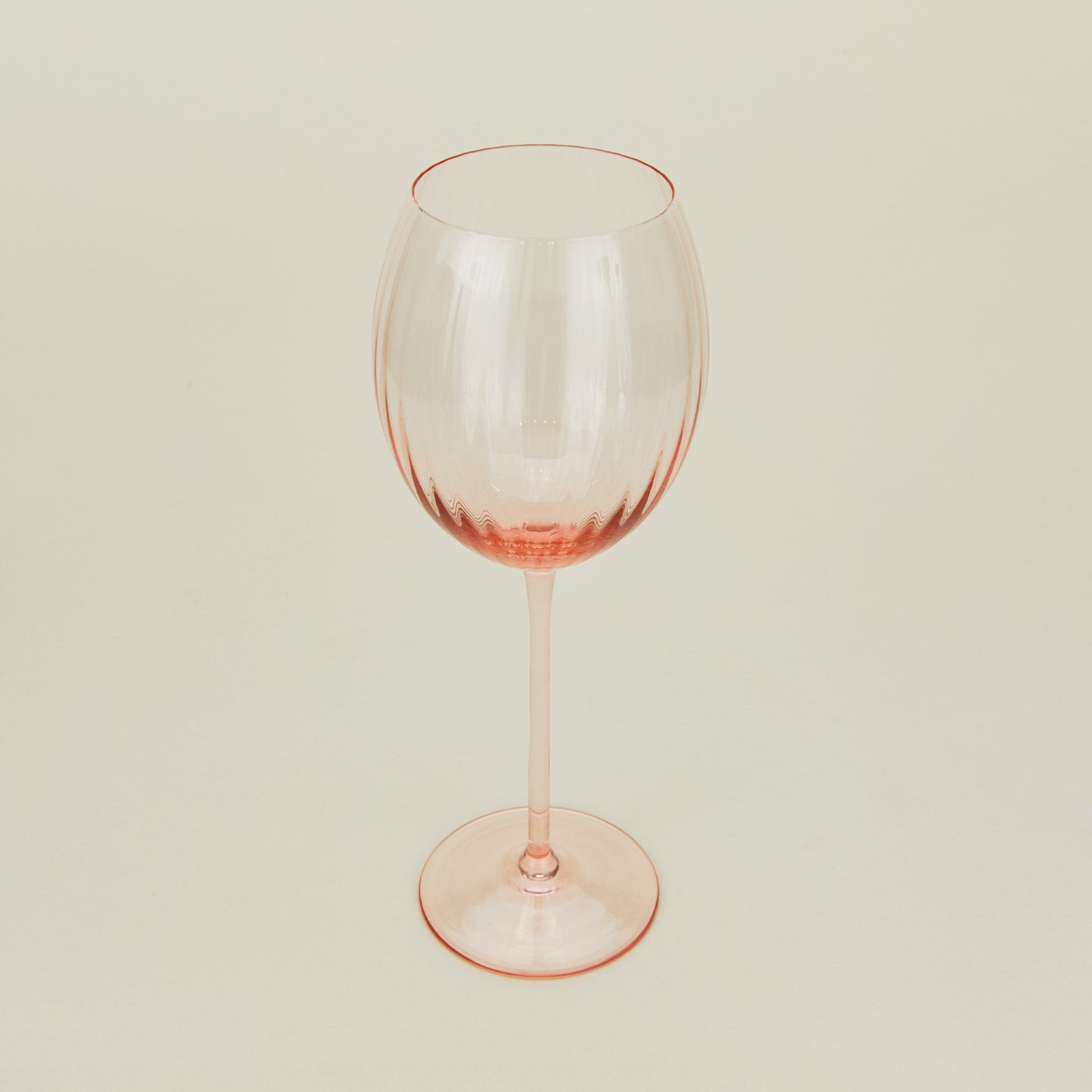 Three-quarter angle of ribbed blush wine glass.