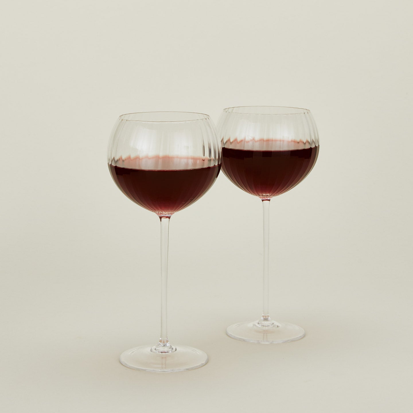 Set of two ribbed  clear wine glasses with red wine.