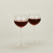 Set of two ribbed  clear wine glasses with red wine.
