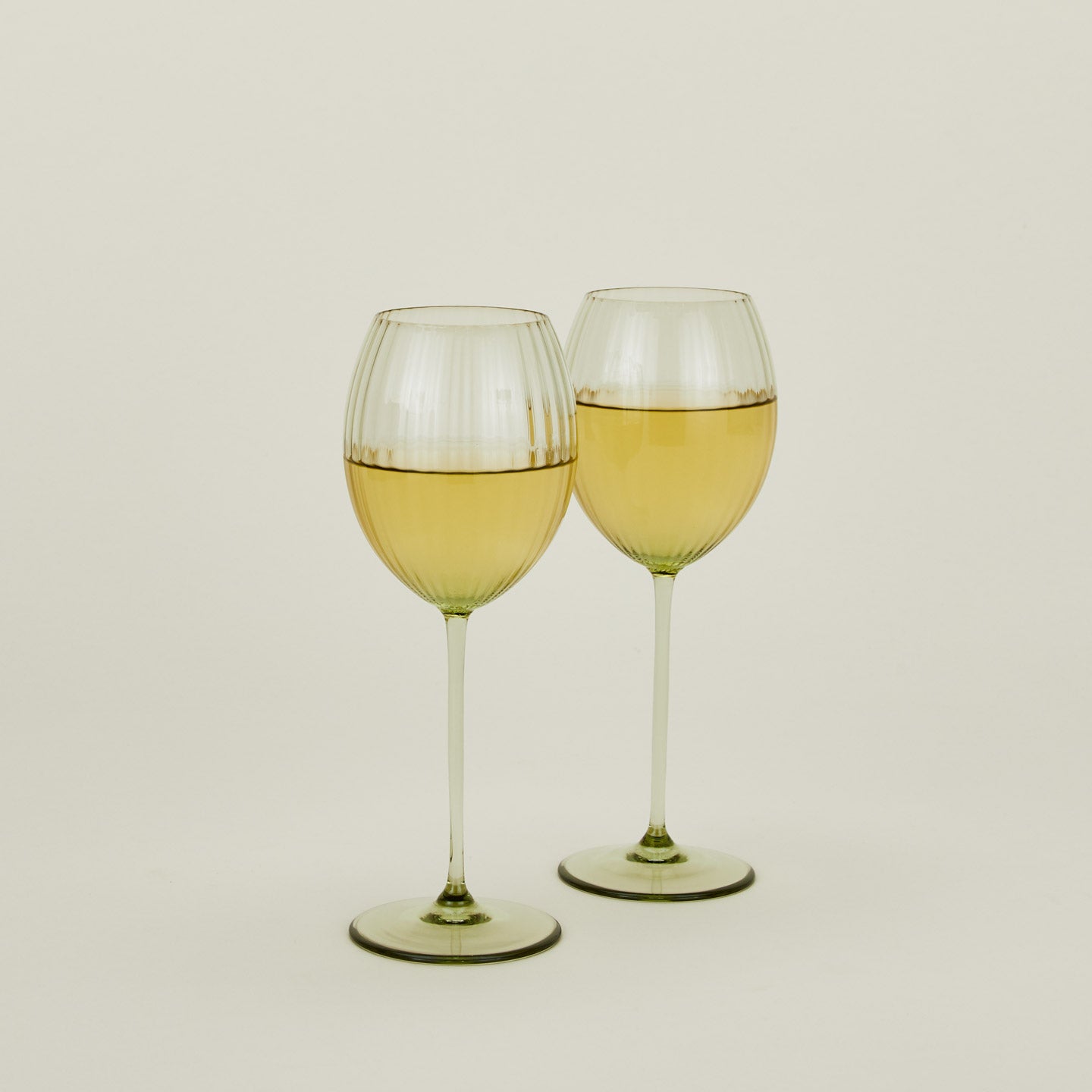 Set of two ribbed olive wine glasses with white wine.