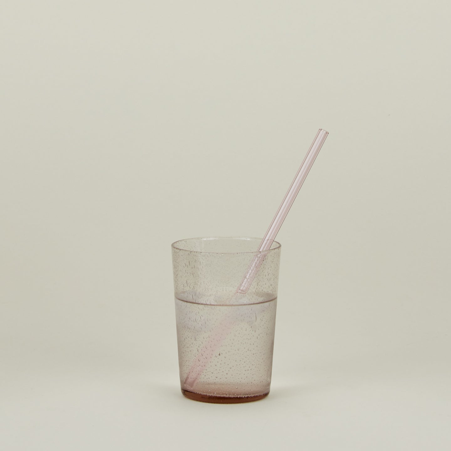 Glass Tumbler in Blush with straw and water.