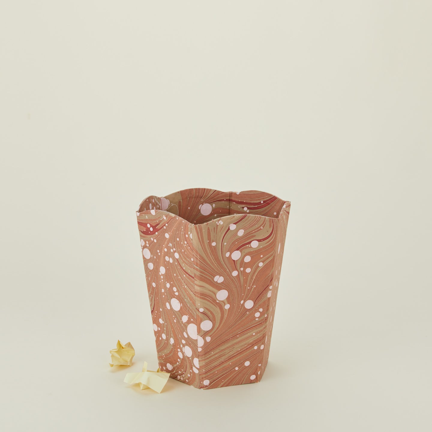 Marbled scalloped wastebasket in mocha with balled-up paper.