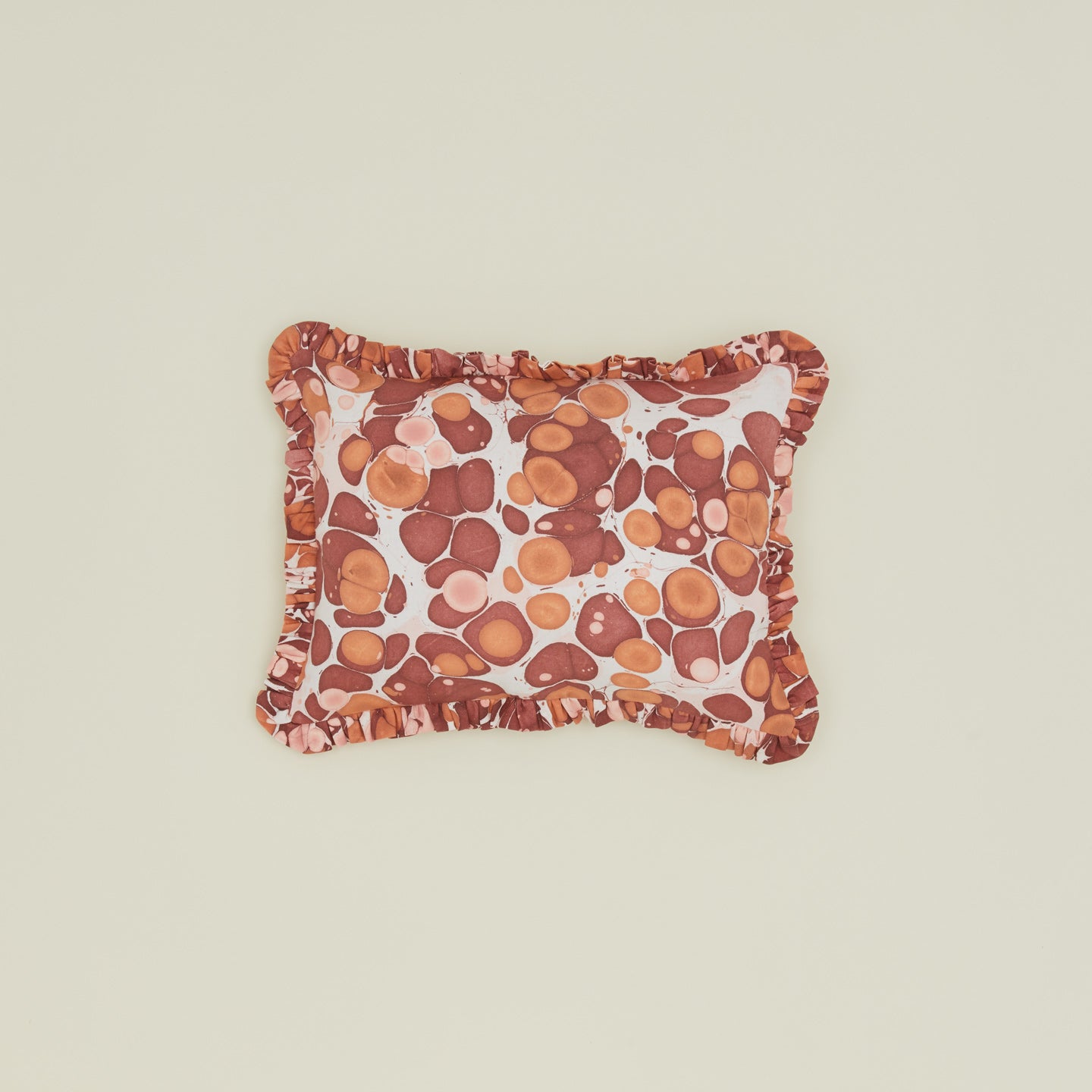 Marbled cotton ruffled pillow in warm tones.