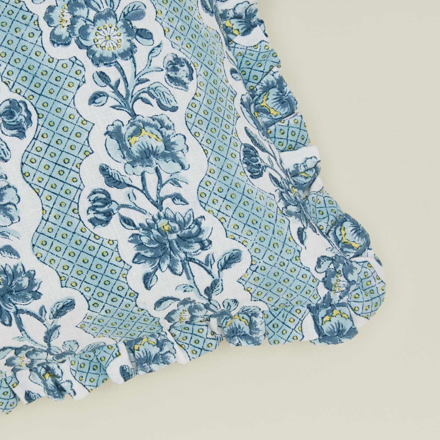 Detail of block printed floral ruffled pillow in indigo.