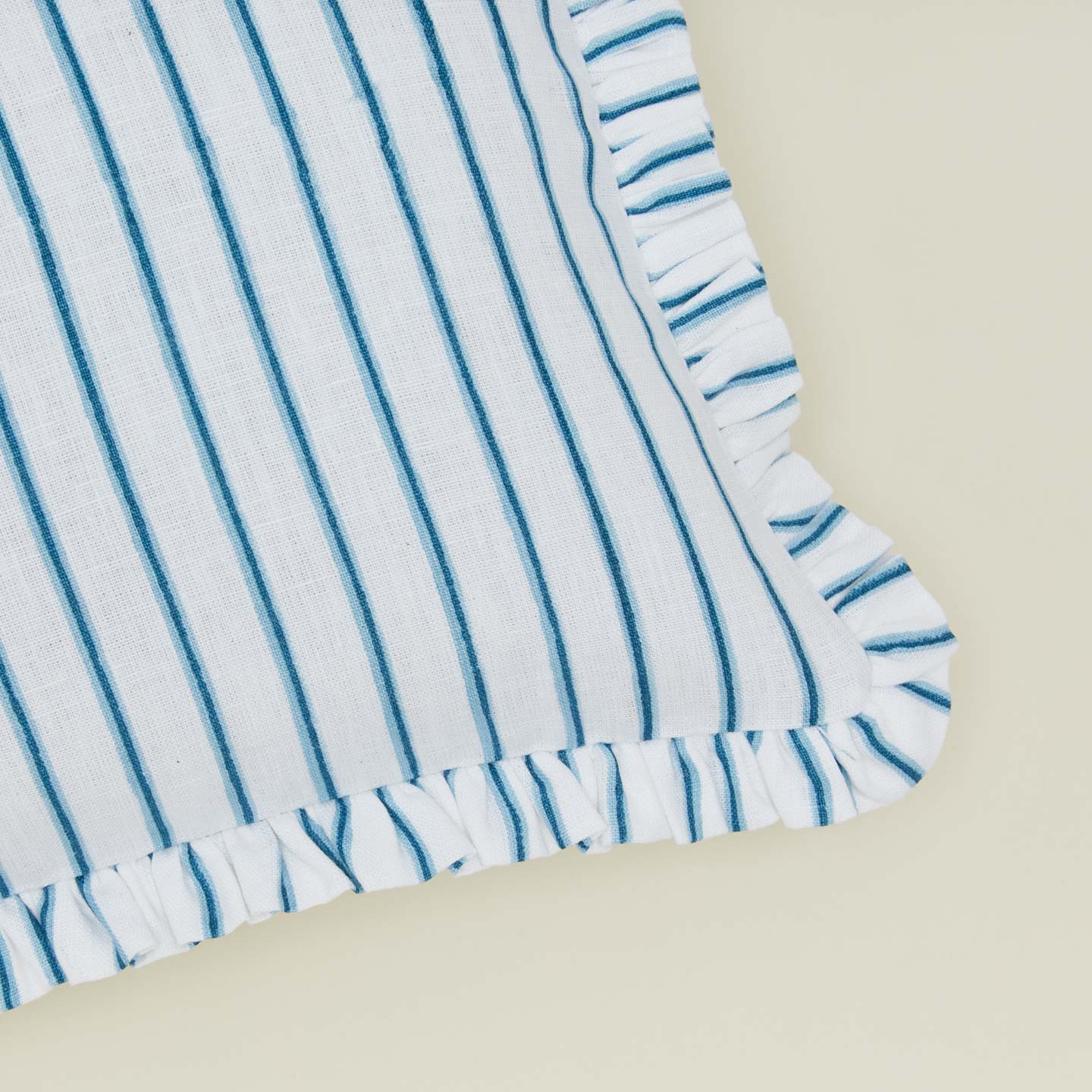 Detail of block printed striped ruffled pillow in indigo.