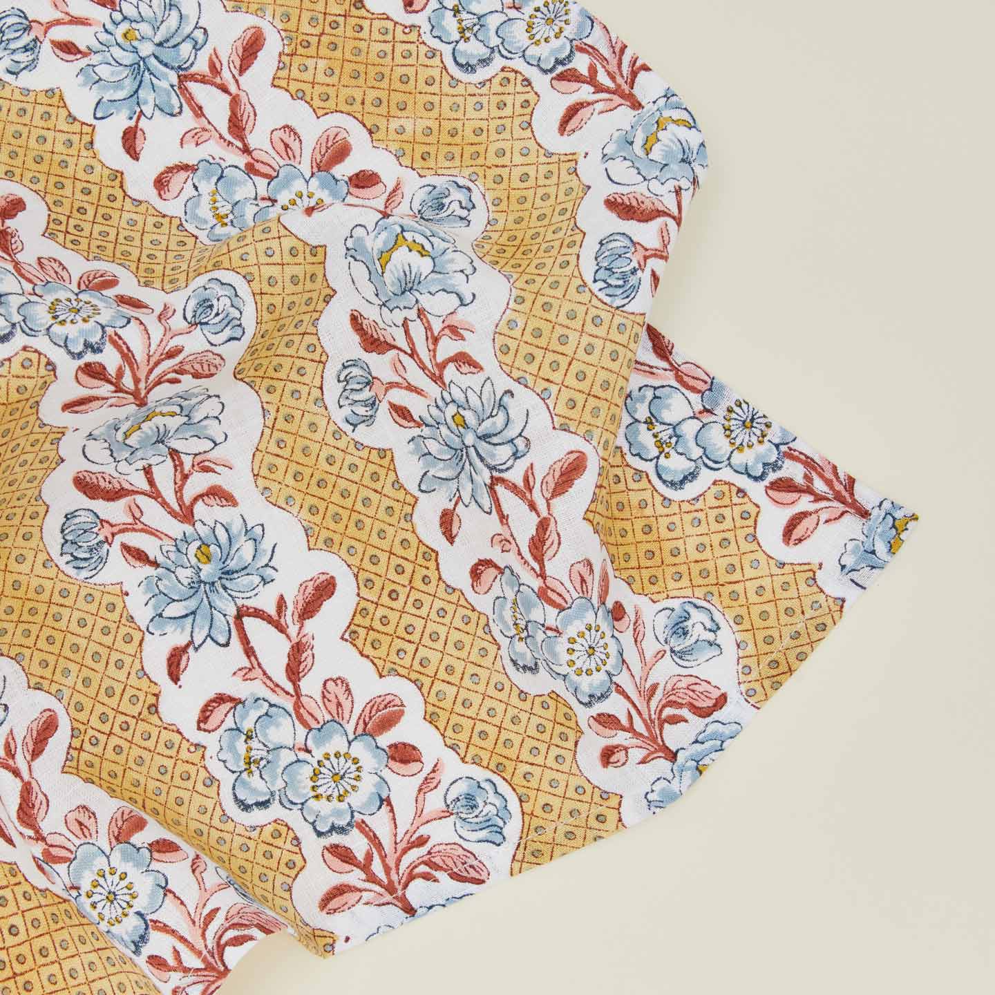 Detail of block printed napkin with a floral pattern in mustard.