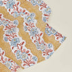 Detail of block printed napkin with a floral pattern in mustard.