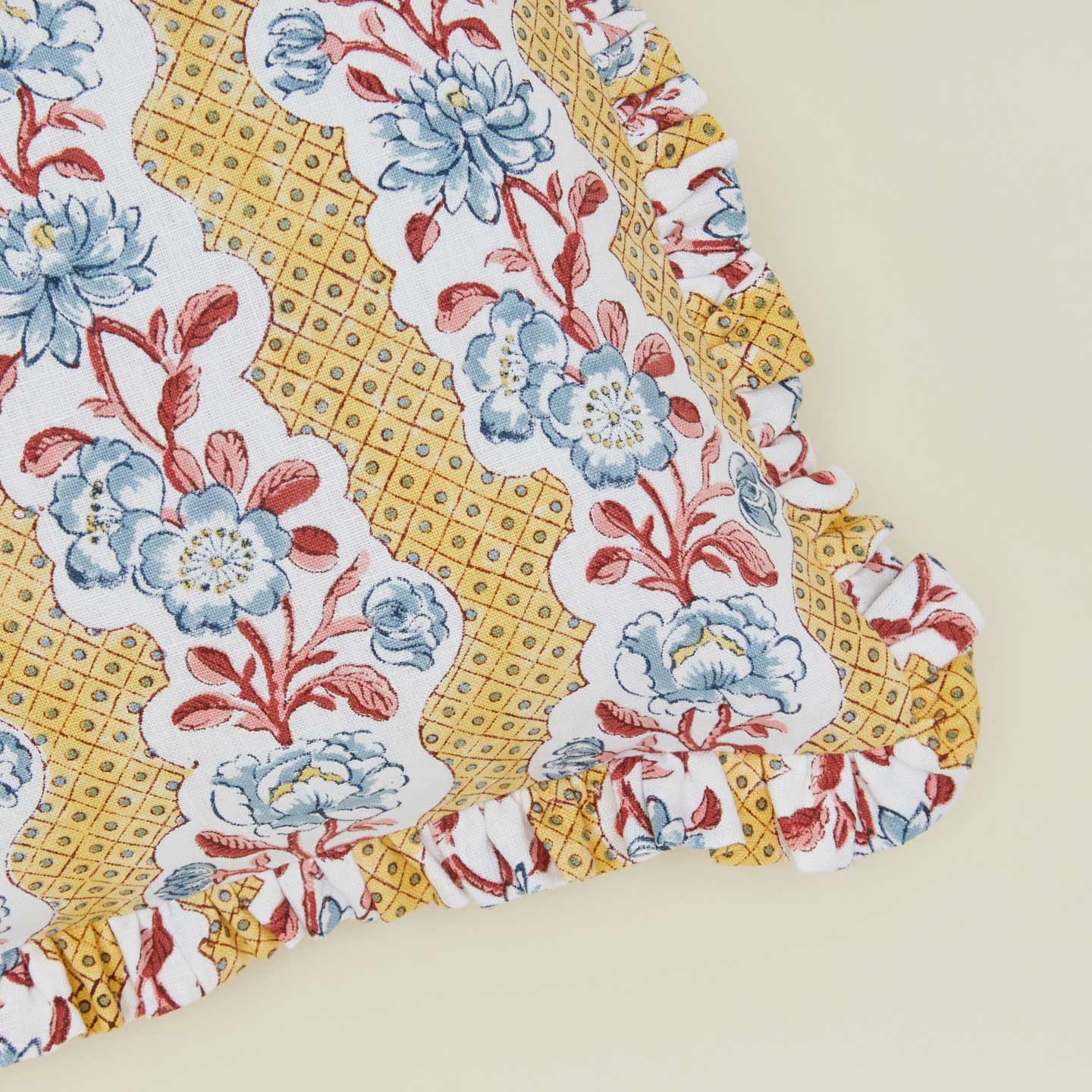 Detail of block printed floral ruffled pillow in mustard.