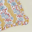 Detail of block printed floral ruffled pillow in mustard.