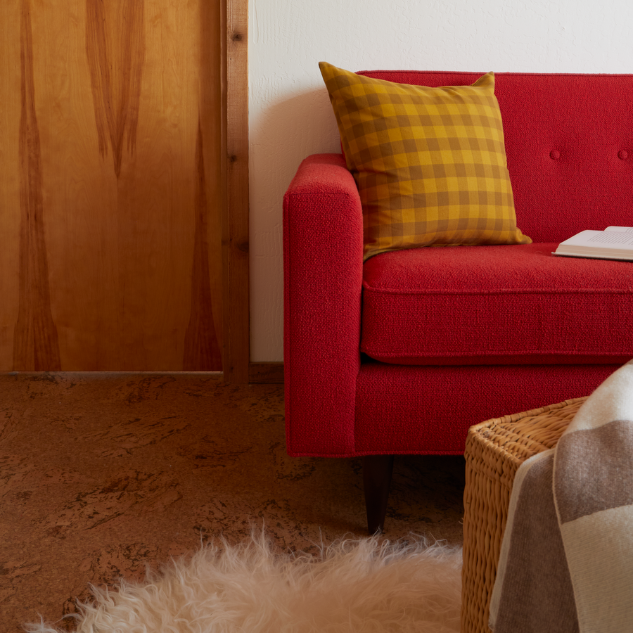 Red sofa with a yellow plaid pillow in a cozy living room setting.