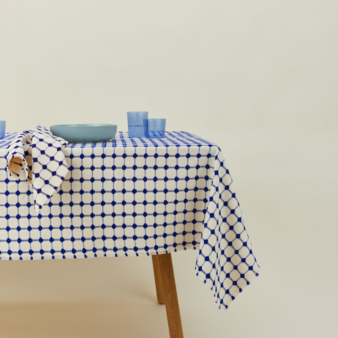 Dove and Donkey wicker fringed tablecloth in cobalt on table with with place setting