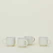Four white ceramic mugs with handles are arranged in a row against a plain, light background.