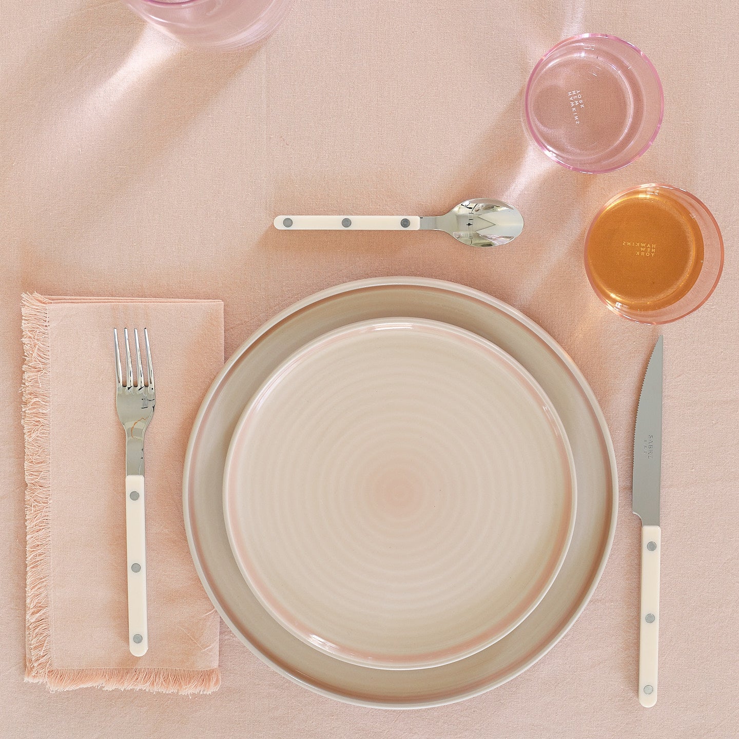 Placesetting of blush pink Essential dinnerware on pink tablecloth.