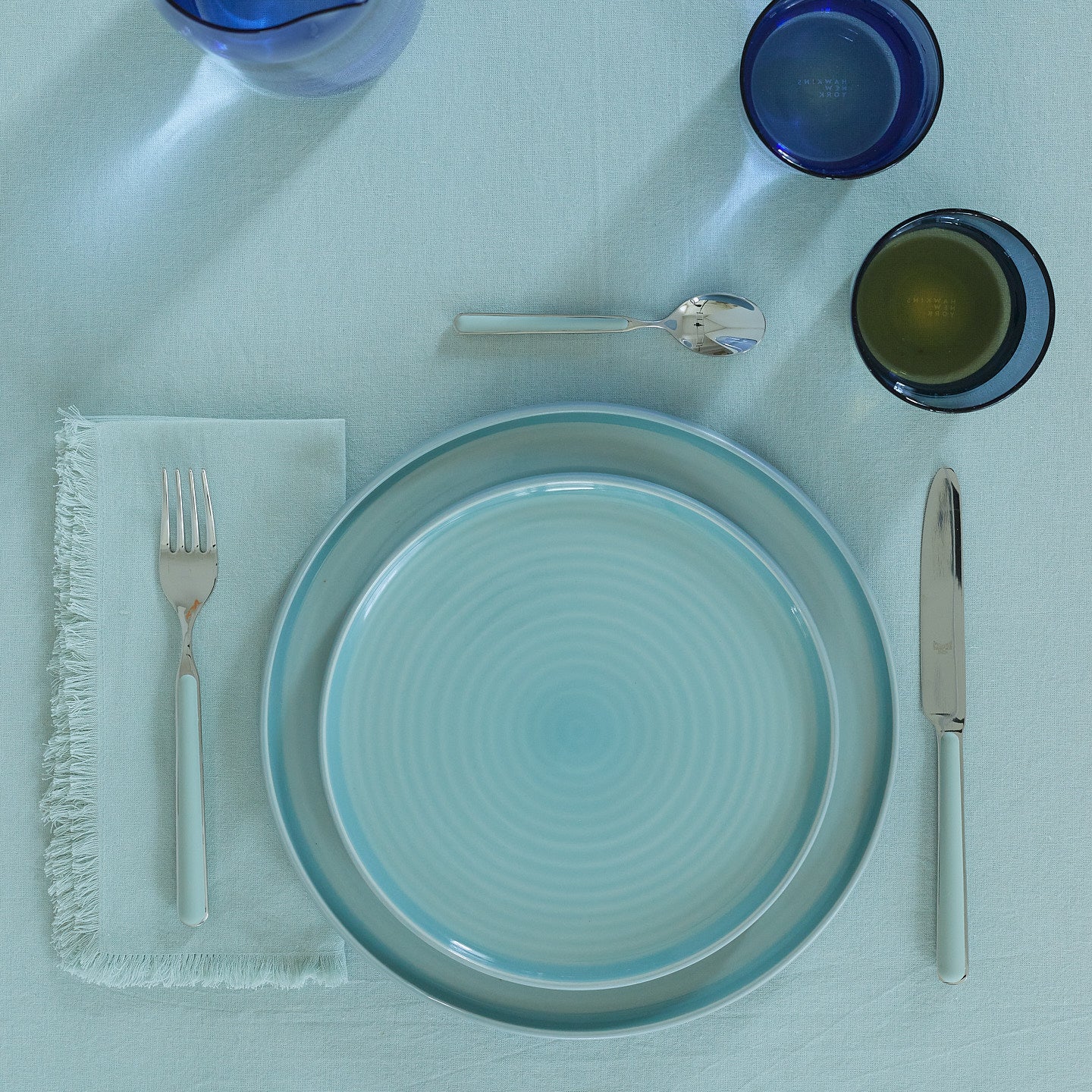 Placesetting with Essential Salad Plate in Sky on blue tablecloth.