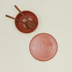 Overhead view of essential serveware set in terracotta with wooden utensils