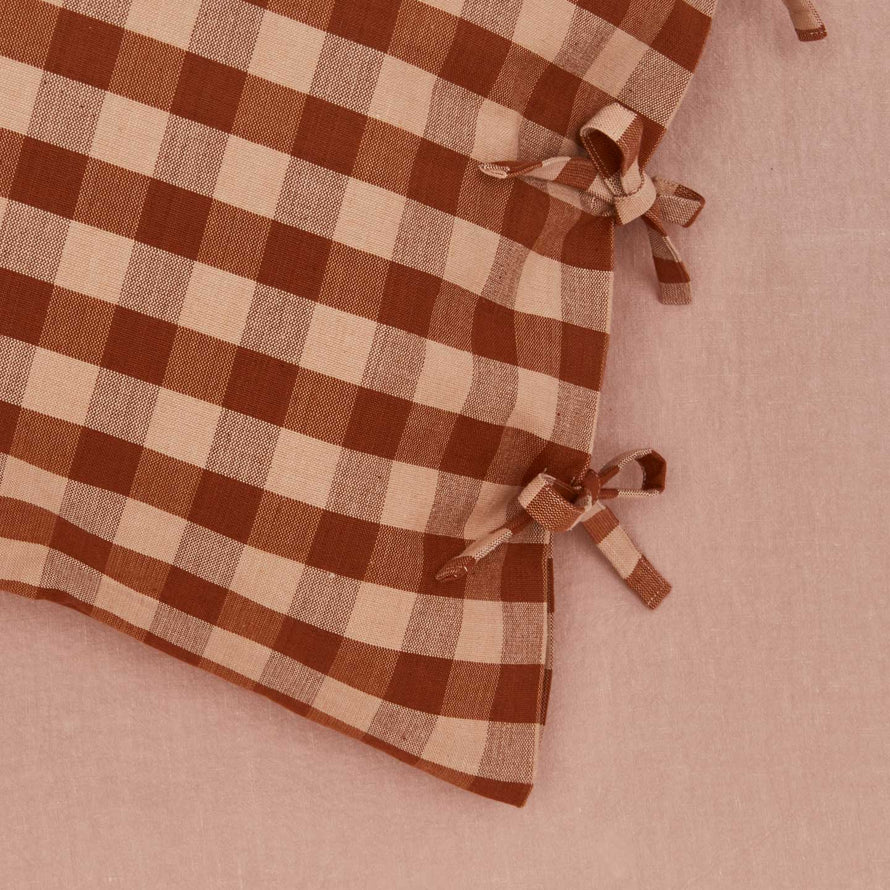 Close up view of essential gingham pillow case in blush/terracotta