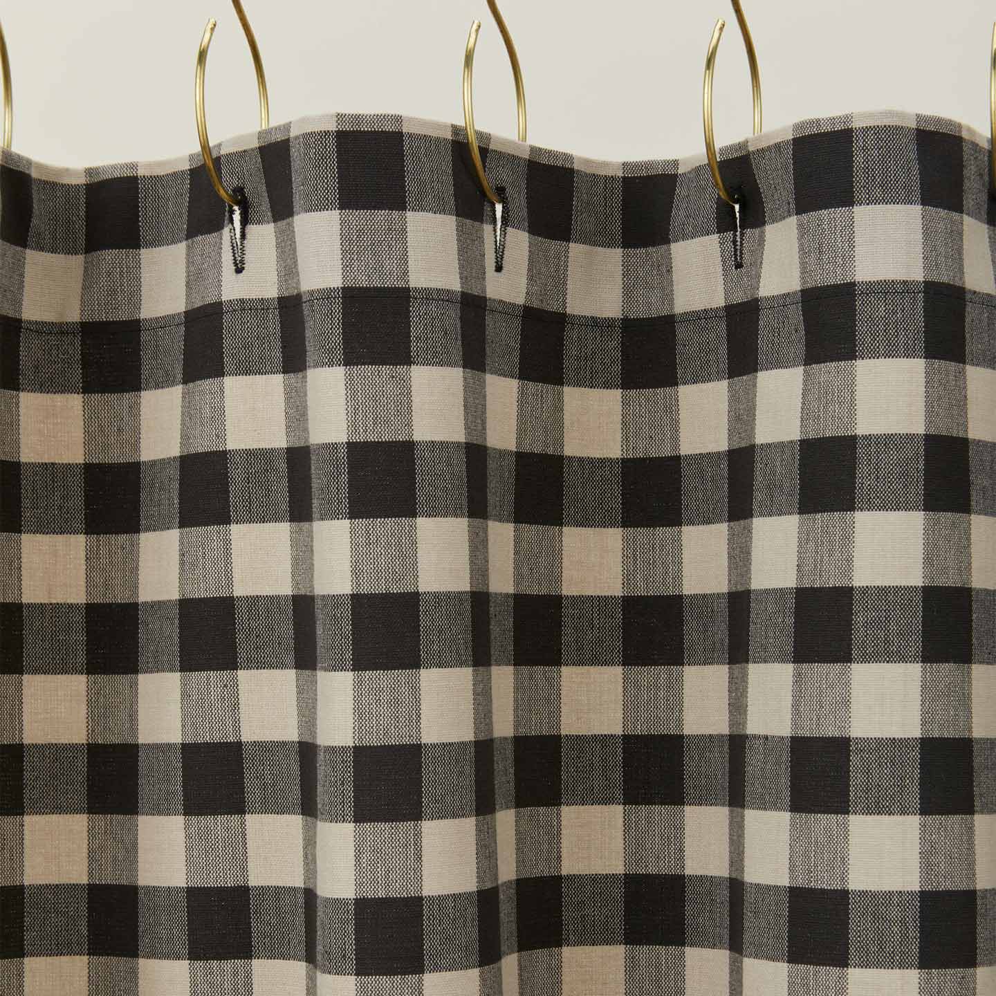 Gingham shower curtain in grey/black on gold curtain hooks.