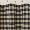 Gingham shower curtain in grey/black on gold curtain hooks.