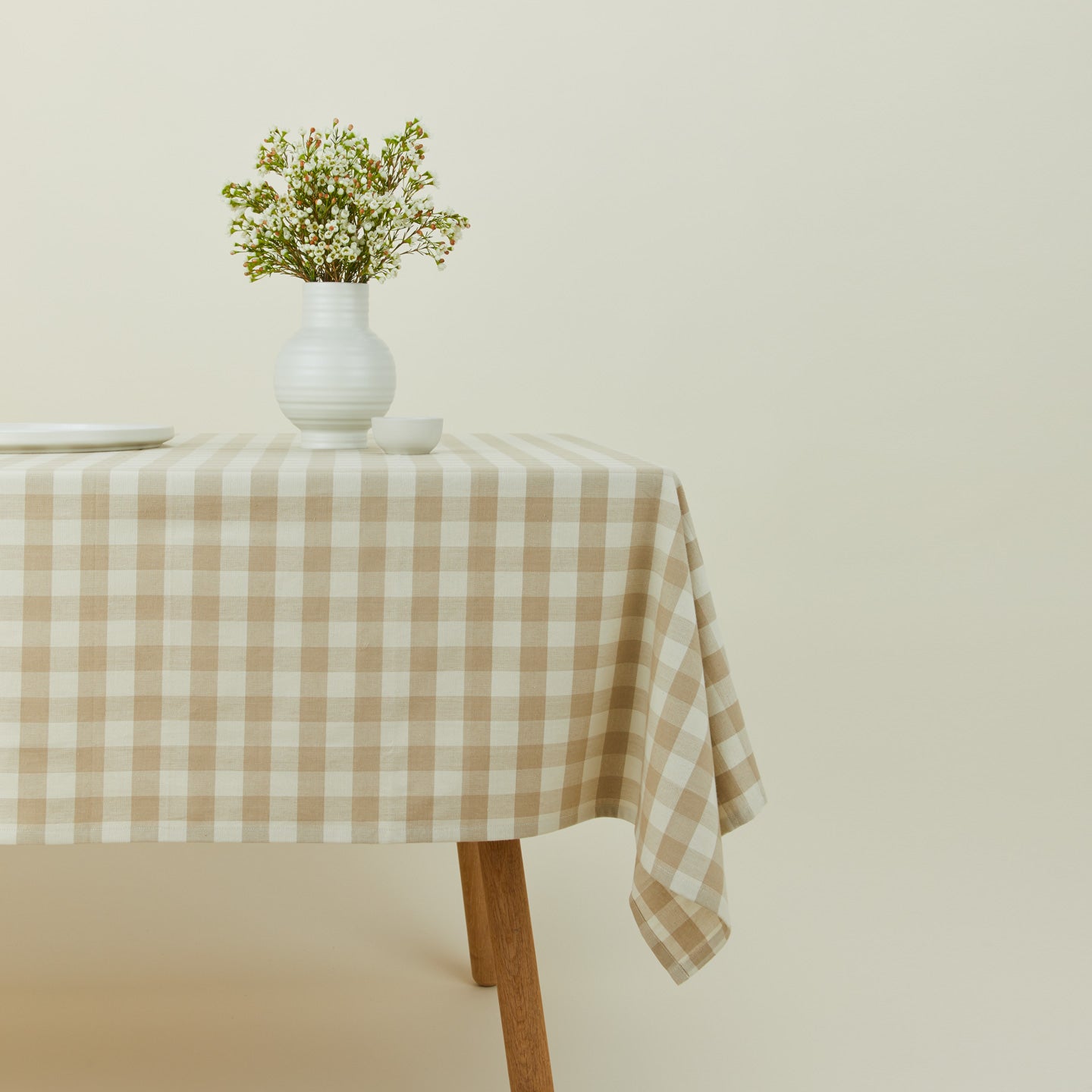 Essential Gingham tablecloth in ivory/flax on a table with florals.