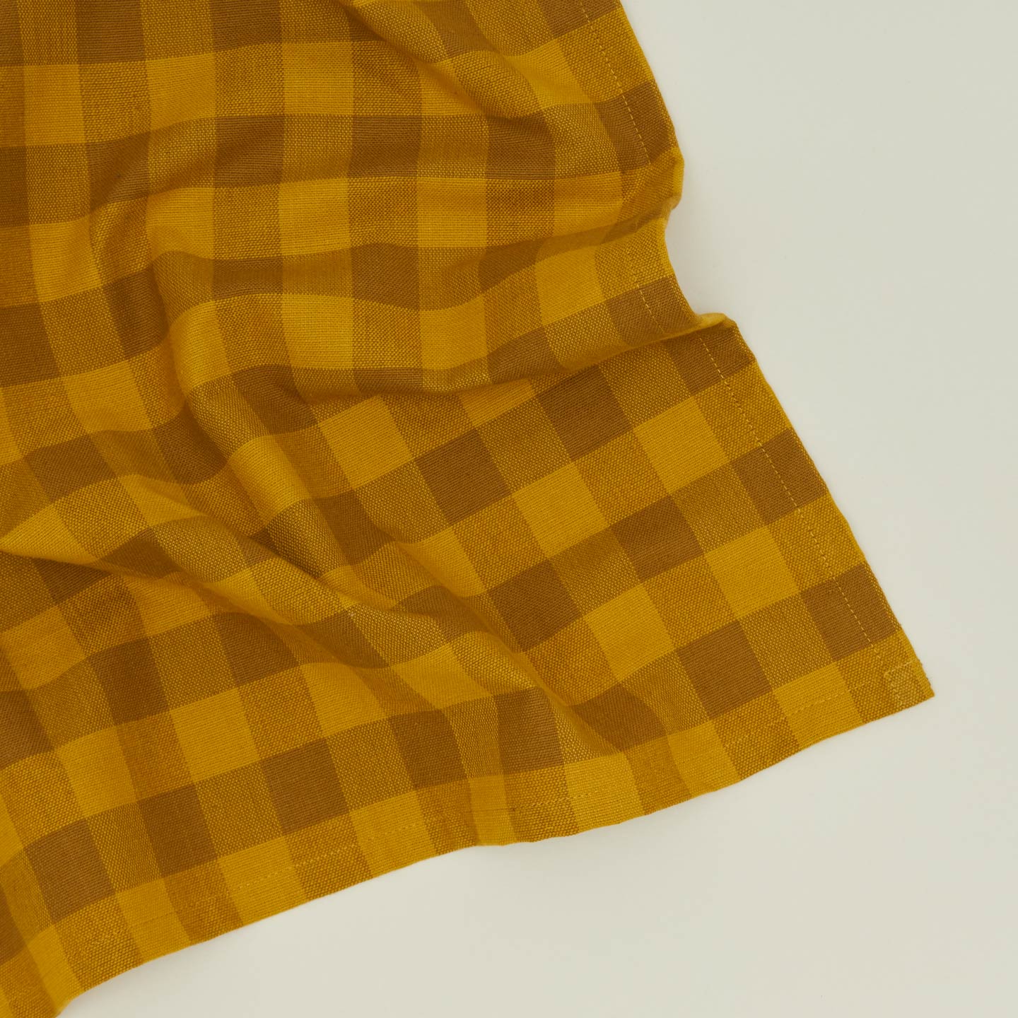 Close up view of Essential Gingham napkin in mustard/bronze