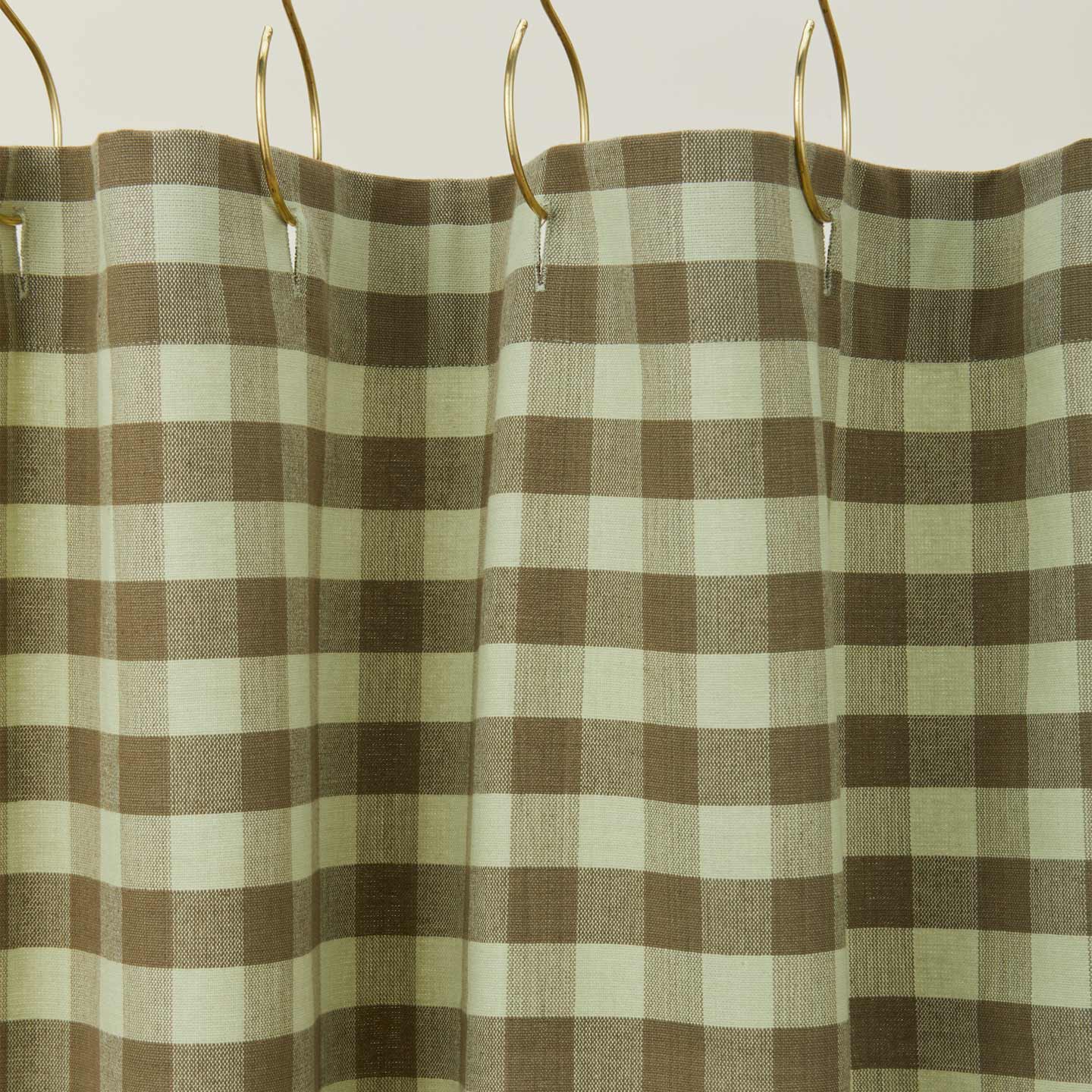 Gingham shower curtain in sage/olive on gold curtain hooks
