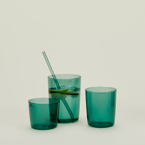 Group of three Essential Glasses in Peacock in various sizes, filled with water and fruit with a coordinating glass straw.
