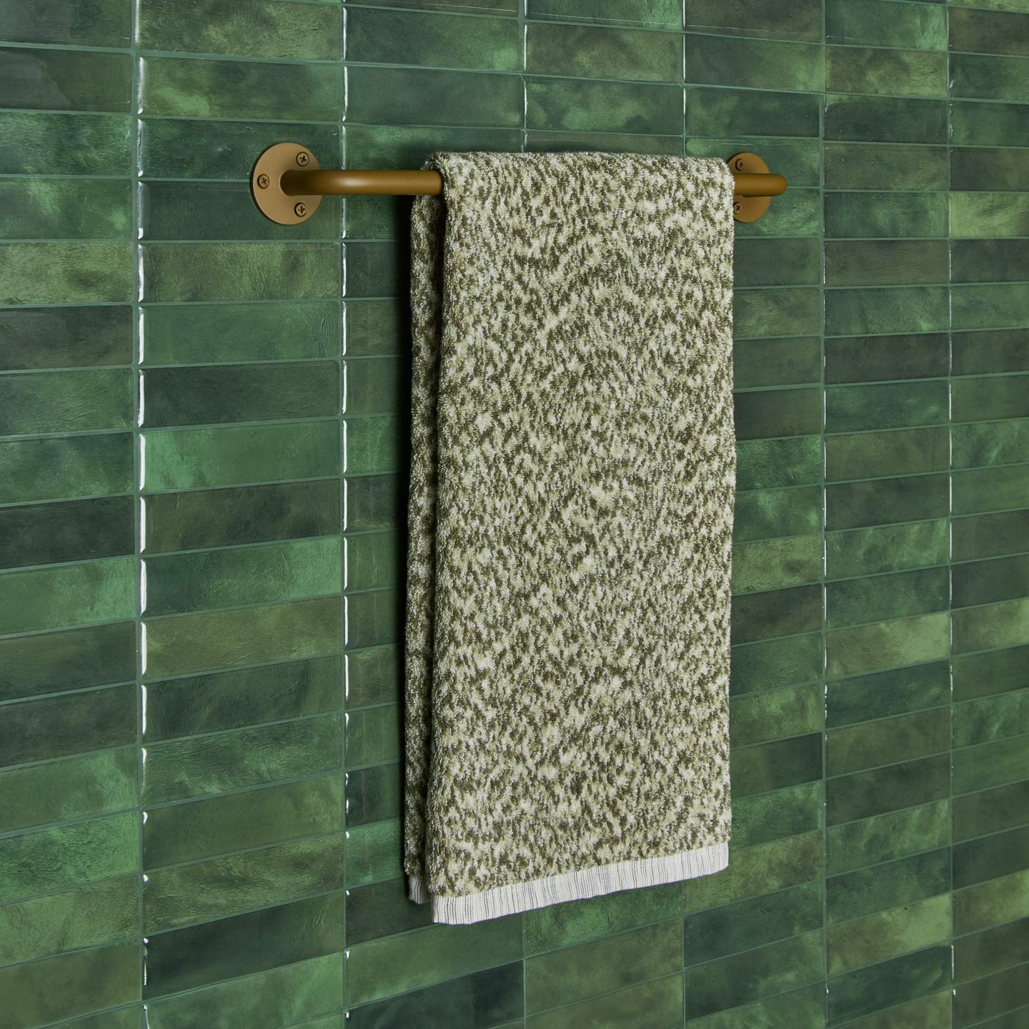 Essential towel bar in Olive with Space Dye terry hand towel in Olive on tiled wall.