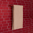Essential towel bar in red on a tile background.