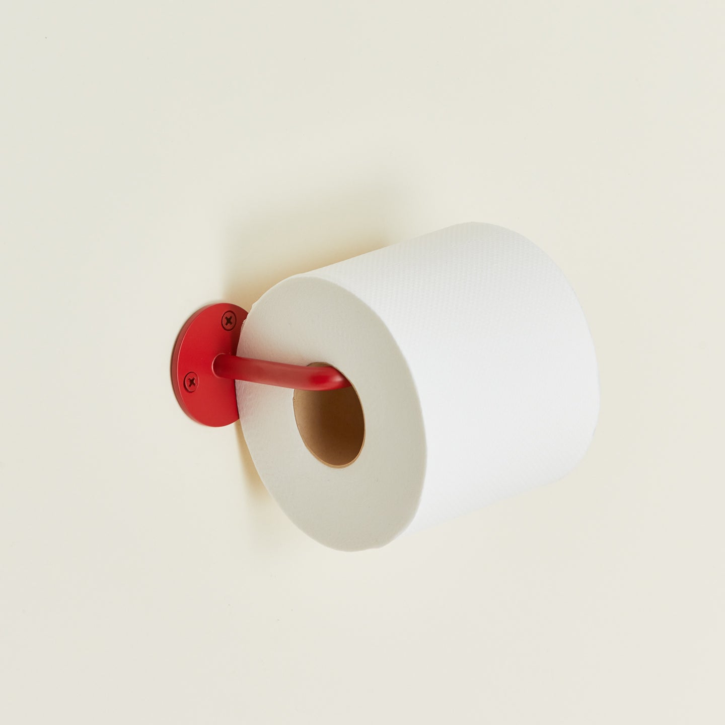 Essential toilet paper holder in red with toilet paper roll